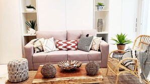 Una sala de estar con sofá, cojines estampados, una mesita de centro y sillas de mimbre.