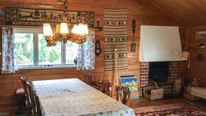 Interior rústico de una cabaña con una mesa de comedor, sillas de madera, chimenea y varios objetos decorativos.