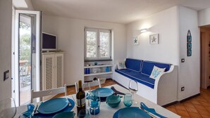 Un ambiente compatto con zona pranzo, divano e televisione.