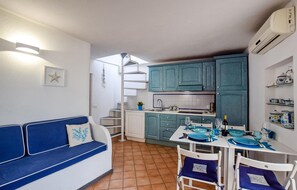 Cozy living space with a kitchenette, sofa, dining table, and stove.
