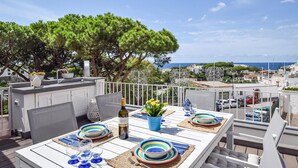 Una terrazza panoramica sul tetto con un tavolo apparecchiato per mangiare, con vista su una cittadina costiera.