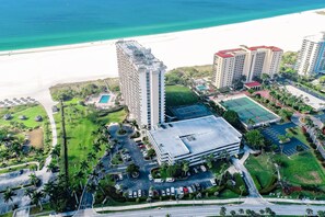 Eine Vogelperspektive zeigt einen Hotelkomplex mit Blick auf den Strand, mehreren Gebäuden und einem Parkplatz.