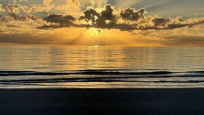 A sunset over a calm sea with a beach in the foreground. - Hello Sunshine!  Eat. Sleep. Beach. Repeat. (Marco Island)