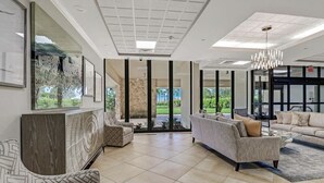 A spacious living room with a large window, a chandelier, and a view of the outdoors. - Hello Sunshine!  Eat. Sleep. Beach. Repeat. (Marco Island)