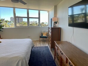 Ein Hotelzimmer mit Bett, Sessel, Kommode und Fernseher an der Wand.