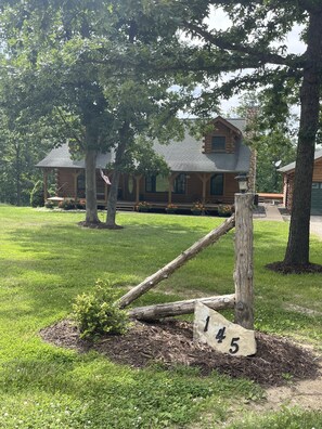 A rustic log cabin with a porch, surrounded by a well-maintained lawn and trees. - Real Log Cabin with Seasonal Pool and Hot Tub with Meramec River Access (Bourbon)