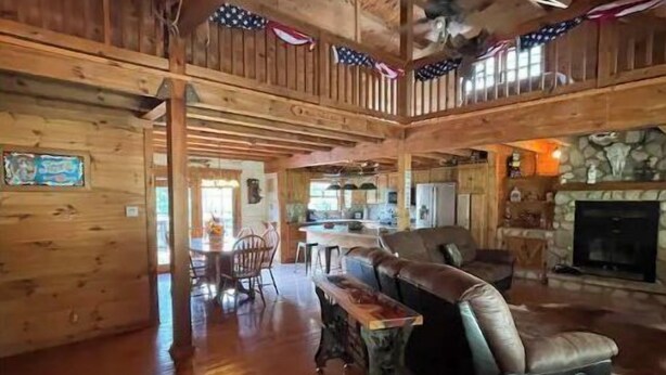 Un intérieur spacieux en bois, avec un plafond haut, une cheminée et un coin repas.