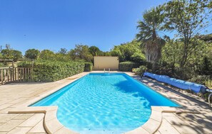 A rectangular swimming pool with a clear blue water surface, surrounded by a paved deck and a wooden fence. - Beautiful home in Fouzilhon (Fouzilhon)