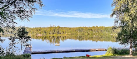 Un lac paisible, avec une jetée qui s’avance sur l’eau, entouré d’une forêt dense et bordé d’un ciel dégagé.