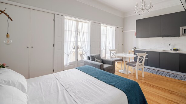 A modern bedroom with a large bed, a small dining table, and a kitchenette. - Estúdio - Zona Histórica de Pombal (Pombal)