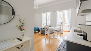 A modern, well-lit room with a dining area, kitchenette, and a large window with curtains. - Estúdio - Zona Histórica de Pombal (Pombal)