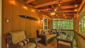 Um deck de madeira aconchegante com móveis de vime, luzes de corda e ventilador de teto.