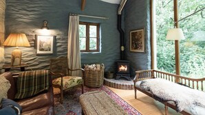 A cozy room with a fireplace, wooden furniture, and large windows. - A quirky converted barn. (Cardigan)
