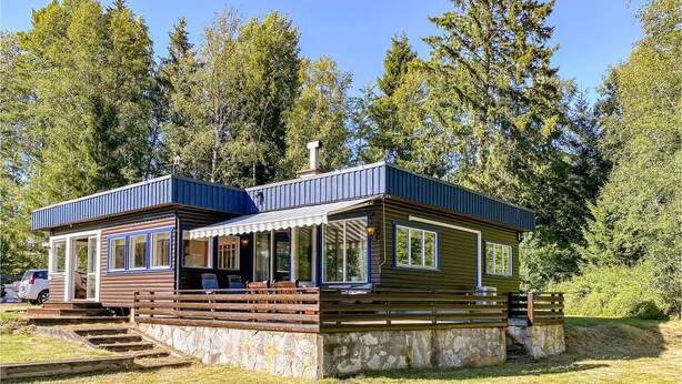 Een chalet met een stenen fundering, houten gevel en een overdekte veranda.