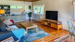 Een gezellige woonkamer met een bank, salontafel, tv-meubel en een boekenplank.