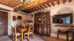 Ein rustikaler Essbereich mit Holztisch und -stühlen, einem großen Holzschrank und einem Kamin aus Stein.