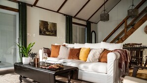 Una sala de estar con un sofá blanco, una mesa de centro negra y una escalera.