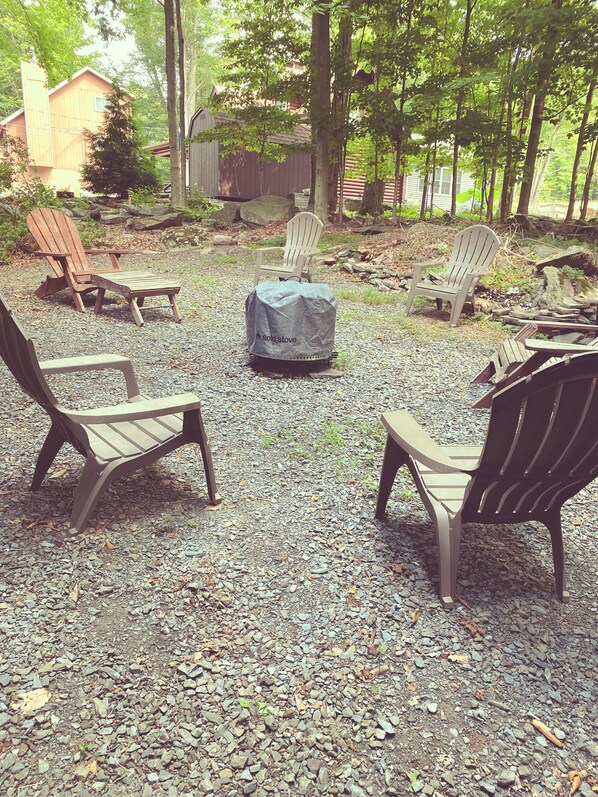 A gravel patio with Adirondack chairs and a covered fire pit.
