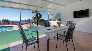 Zona exterior coberta amb piscina, gandules i taula amb cadires.