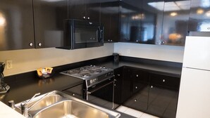 Una cocina moderna con gabinetes negros, electrodomésticos de acero inoxidable y un lavamanos doble.
