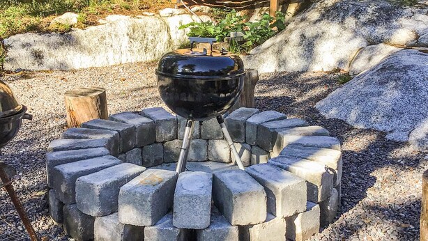 A circular stone fire pit with a black grill in the center, surrounded by a gravel area. - 4 bedroom cozy home in Brottby (Brottby)