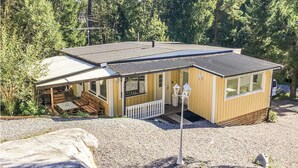 A small, single-story cabin with a porch, a covered outdoor seating area, and a gravel driveway. - 4 bedroom cozy home in Brottby (Brottby)