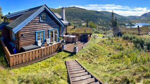 A wooden cabin with a deck, outdoor seating, and a view of a lake and mountains. - Nice home in Rjukan with WiFi (Rjukan)