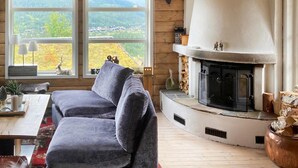 A cozy living room with a large window, a fireplace, and a comfortable sofa. - Nice home in Rjukan with WiFi (Rjukan)
