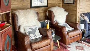 Two leather armchairs with fur throws and moose pillows, a small table with a candle, and a patterned rug. - Nice home in Rjukan with WiFi (Rjukan)