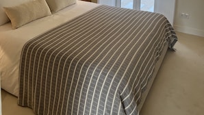 Een slaapkamer met een groot bed, een ronde spiegel en een schuifglazen deur naar een balkon.