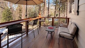 Eine Holzdar Terrasse mit Tisch, Stühlen und einer großen Schirmstange.