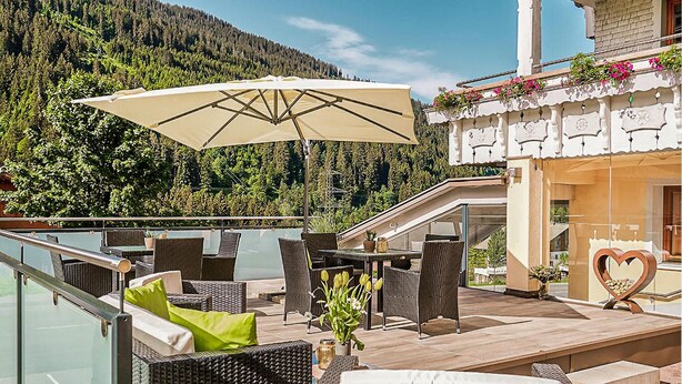 Eine Terrasse mit Korbmöbeln, einem Tisch und einem Sonnenschirm.