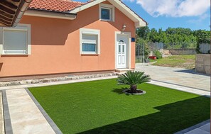 A house with a well-maintained lawn, a small palm tree, and a white door.