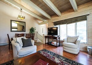 Relax in this spacious living room with a high ceiling, featuring a sofa, armchair, and flat-screen TV.