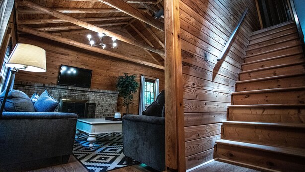 Un interior de madera con una escalera, una chimenea y un sofá.
