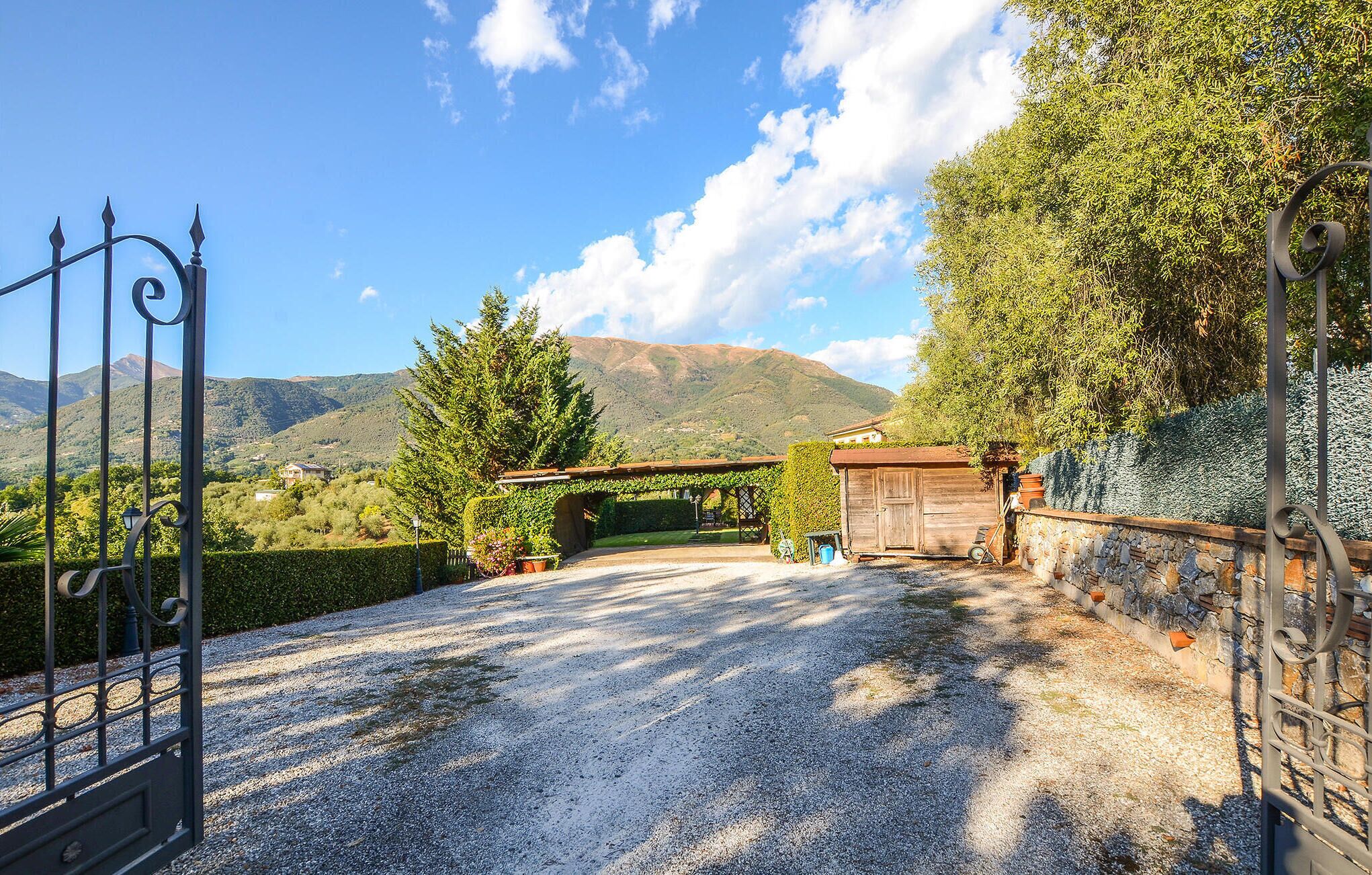 A gravel driveway leading to a wooden gate with a mountain backdrop.