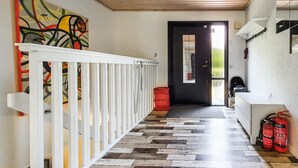 A hallway with a white railing, a colorful abstract painting, a black door, and a fire extinguisher on the right. - 6 bedroom pet friendly home in Vittaryd (Vittaryd)