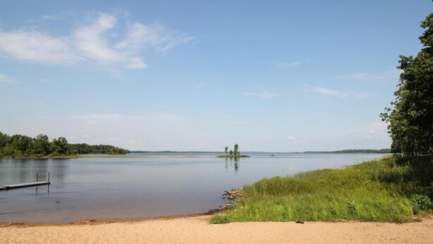A calm lake with a sandy beach and grassy areas. - 6 bedroom pet friendly home in Vittaryd (Vittaryd)