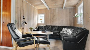 En moderne stue med en sort lædersofa, et rundt sofabord og en læderlænestol.