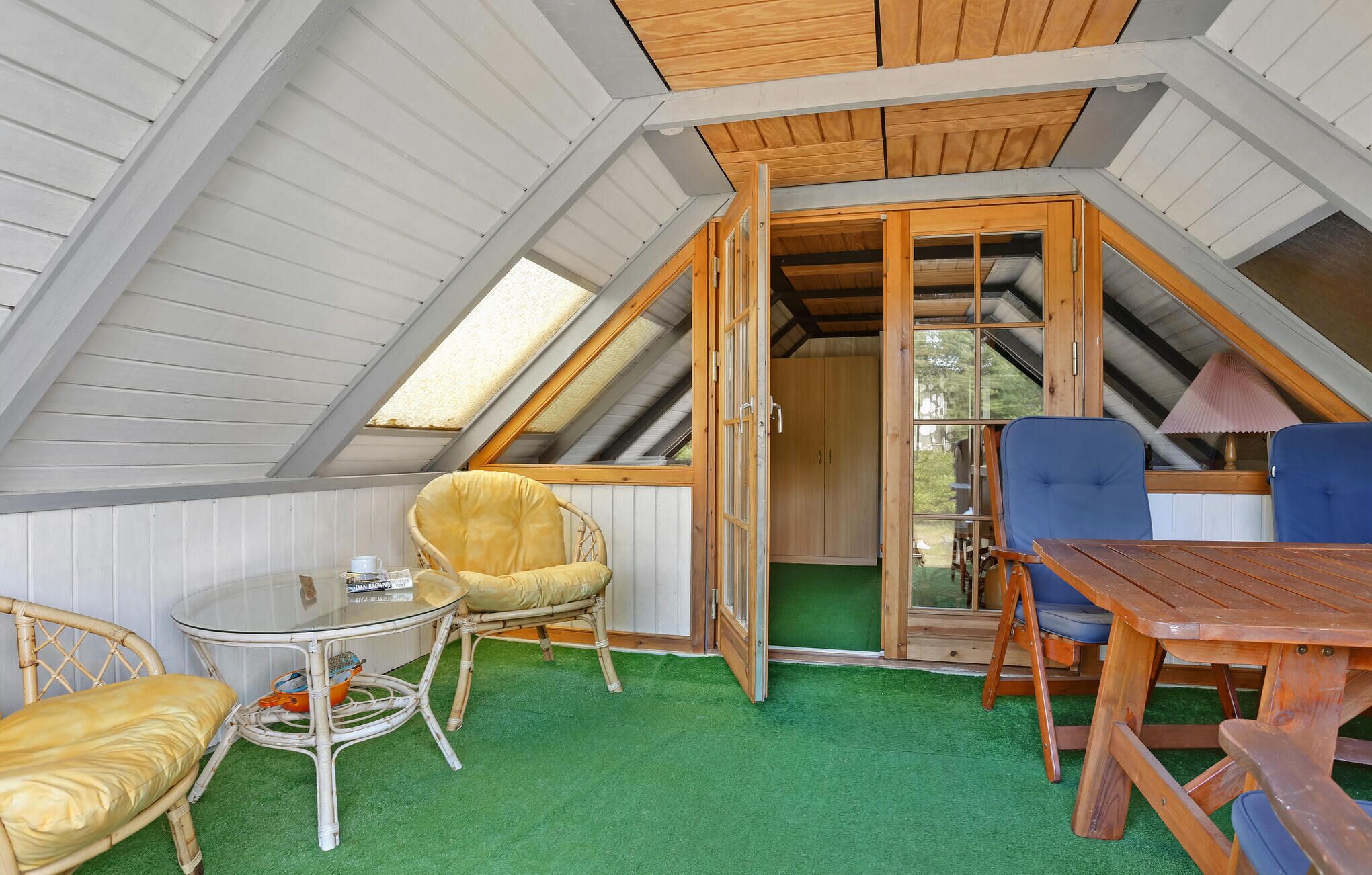 Une pièce mansardée chaleureuse, avec une table en bois, deux chaises et une table en verre.
