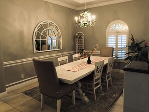 Un espace repas comprenant une table, des chaises, un lustre et des éléments décoratifs.