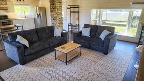 A modern living room with two dark sofas, a wooden coffee table, and a patterned rug. - Quiet 2 story Cabin on 32 acres near eleven point river (Alton)