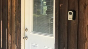 A white door with a window, a doorbell, and a wooden exterior. - Quiet 2 story Cabin on 32 acres near eleven point river (Alton)