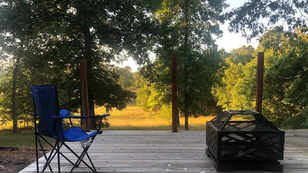 A wooden deck with a blue folding chair and a black grill. - Quiet 2 story Cabin on 32 acres near eleven point river (Alton)