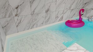 A bathroom with a marble tiled wall and a bathtub with a pink flamingo float. - Awesome home in Nibe with kitchen (Nibe)