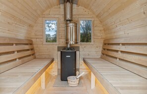 A sauna room with wooden walls, two windows, a central heating unit, and a wooden bench. - Awesome home in Nibe with kitchen (Nibe)