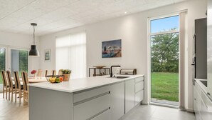 A modern kitchen with a large island, white cabinetry, and a view of the outdoors. - Awesome home in Nibe with kitchen (Nibe)
