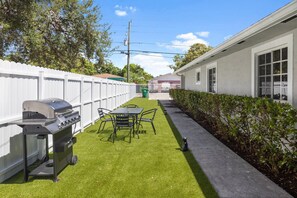 Un jardin avec un barbecue, une table et des chaises.