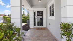 A covered porch with a white door, a small window, and a light fixture above. - 8 bedrooms - Stunner in Miami Design District! (Miami)