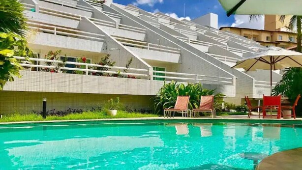 Une piscine à l’eau d’un bleu cristallin, entourée de chaises longues et de parasols.